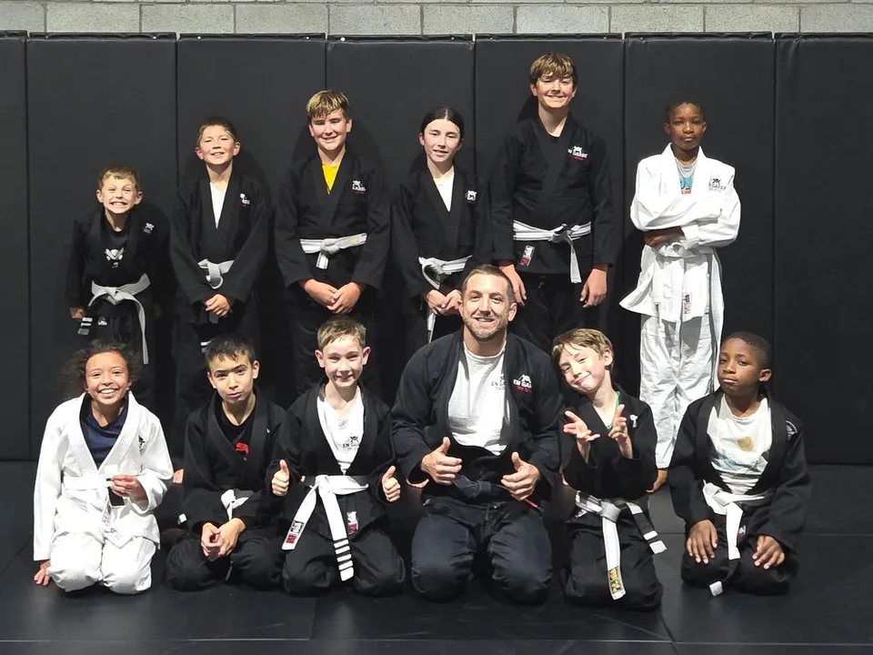 Groupe d'enfants en gi avec leur instructeur, club En Garde Jiu-Jitsu